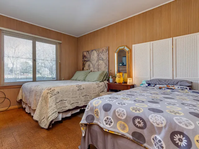 a bedroom with two beds and a dresser next to a window