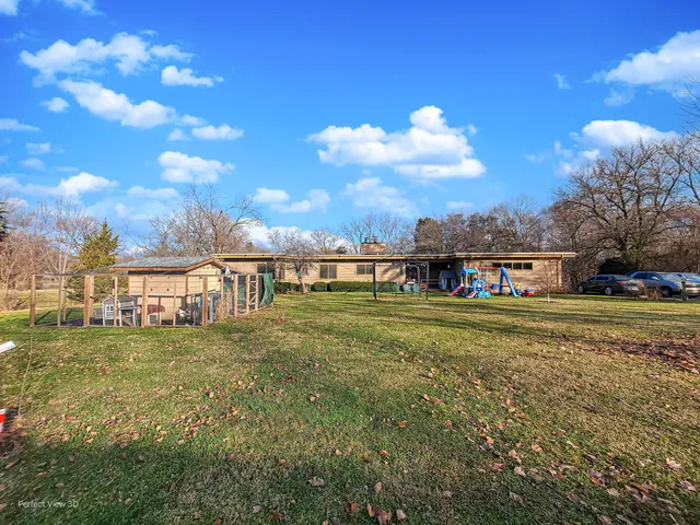 a view of a big house with a big yard and large trees
