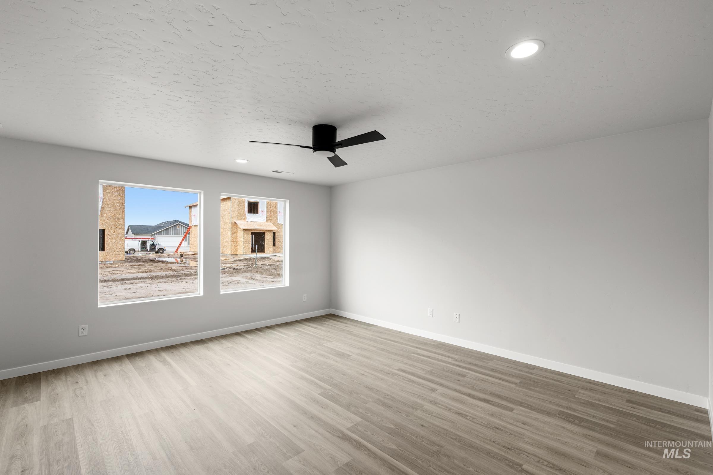 14056 Shiny Spruce Street Caldwell, ID 83607 - Photo 7 of 25 Spacious room featuring wood-finish flooring, two large windows, a ceiling fan, and recessed lighting