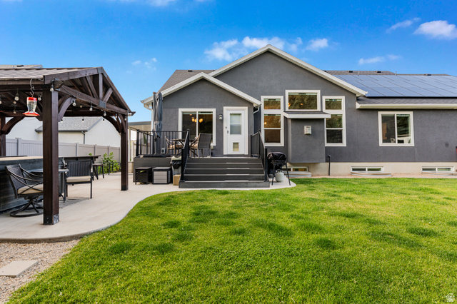 313 Old Maple Road South Weber, UT 84405 - Photo 27 of 35 Spacious backyard featuring a manicured lawn, a large concrete patio with an adjacent wood pergola, and a multi-level deck with dark composite steps