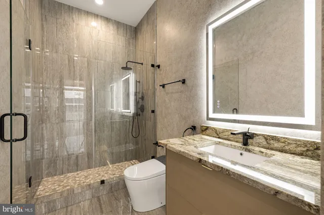 a bathroom with a granite countertop sink toilet and shower