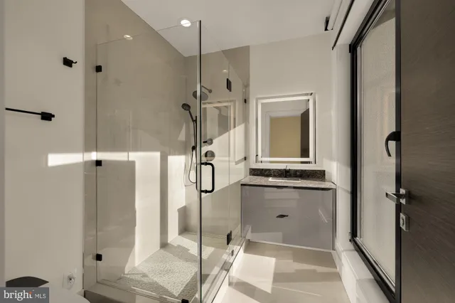 a bathroom with a granite countertop sink a mirror and shower