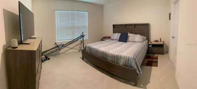 a bedroom with a bed and a flat tv screen on a dresser