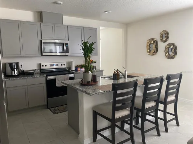 a kitchen with stainless steel appliances granite countertop a table chairs microwave and sink