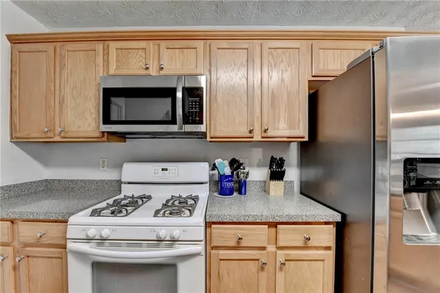 a kitchen with stainless steel appliances granite countertop a refrigerator stove and sink