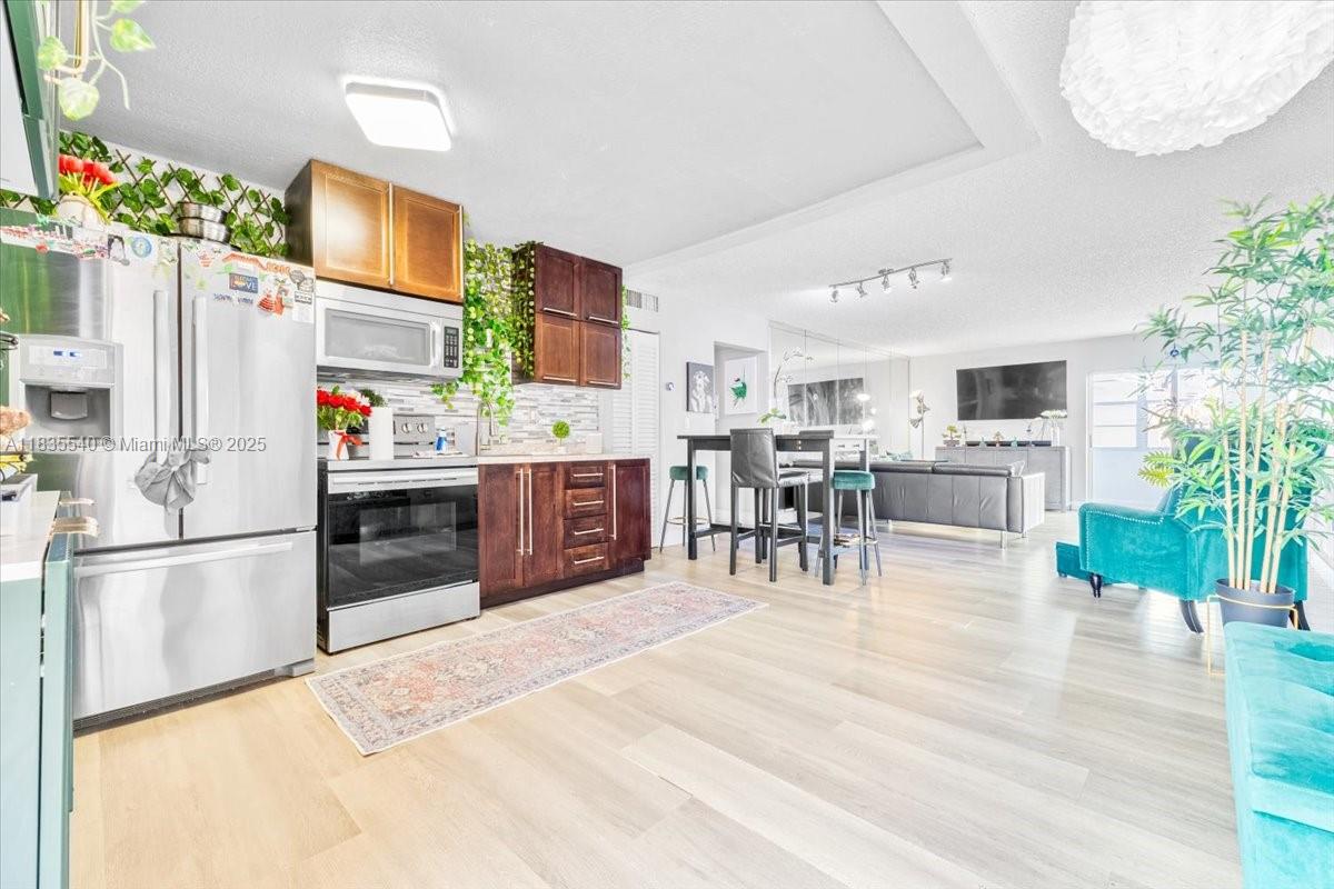 a kitchen with stainless steel appliances kitchen island granite countertop a refrigerator and microwave