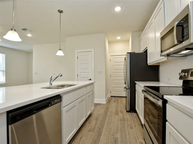 a kitchen with a sink stainless steel appliances a counter space and cabinets