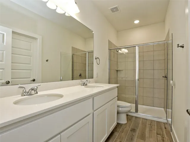 a bathroom with a sink double vanity granite toilet and shower
