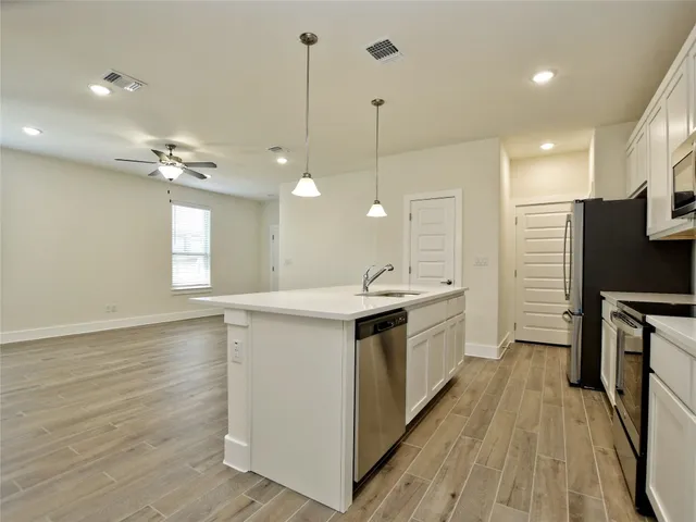 a large kitchen with kitchen island a white counter space a sink a window and stainless steel appliances