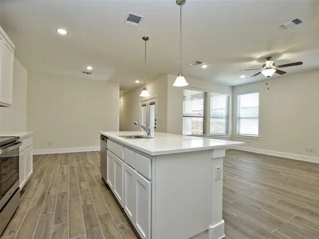 a kitchen with a stove a sink and wooden floor
