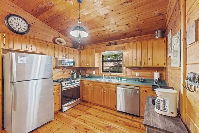 a kitchen with a refrigerator a stove a sink and a clock on the wall