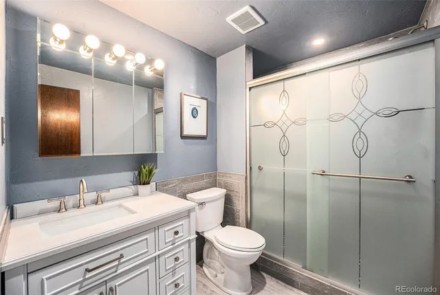 a bathroom with a granite countertop sink a toilet and a mirror
