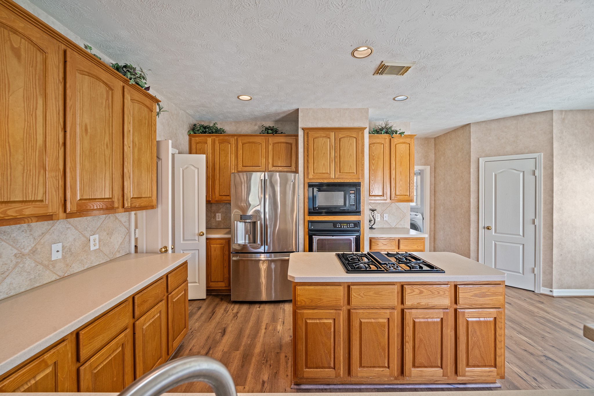 9306 Lochflora Drive Spring, TX 77379 - Photo 13 of 48 a kitchen with stainless steel appliances granite countertop a refrigerator a stove a sink dishwasher and wooden cabinets with wooden floor