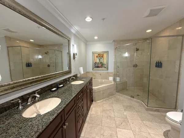 a bathroom with a granite countertop double vanity sink toilet mirror and shower