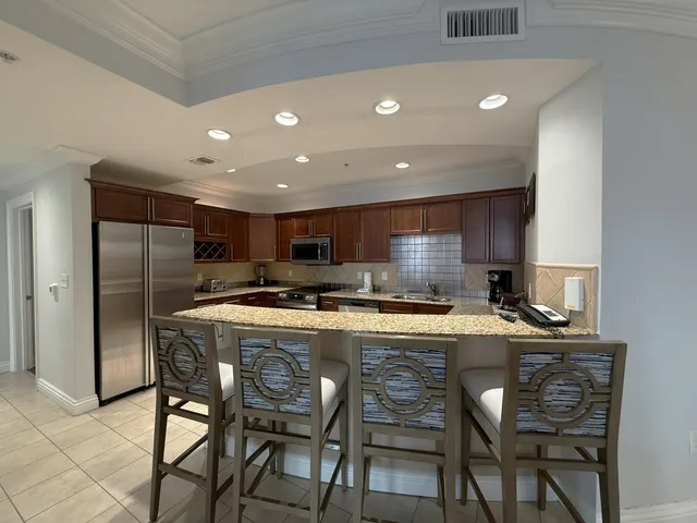 a kitchen with stainless steel appliances granite countertop a table chairs sink and white cabinets