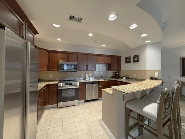 a kitchen with stainless steel appliances granite countertop a stove top oven a sink dishwasher and a refrigerator