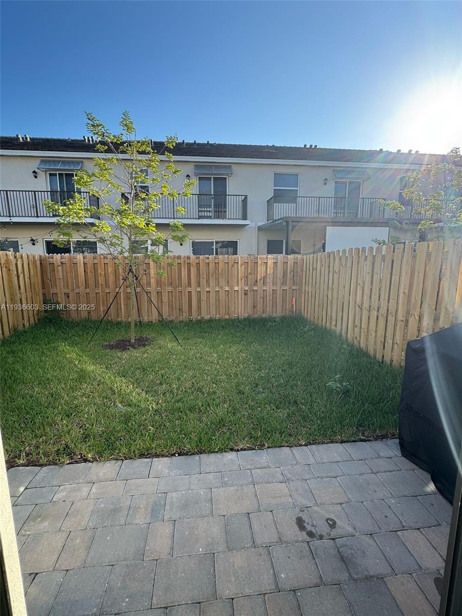 141 Northeast 13th Circle Homestead, FL 33033 - Photo 19 of 19 a view of a backyard with lawn chairs floor to ceiling window and wooden fence