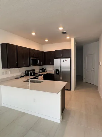 a large kitchen with kitchen island a large counter top stainless steel appliances and cabinets