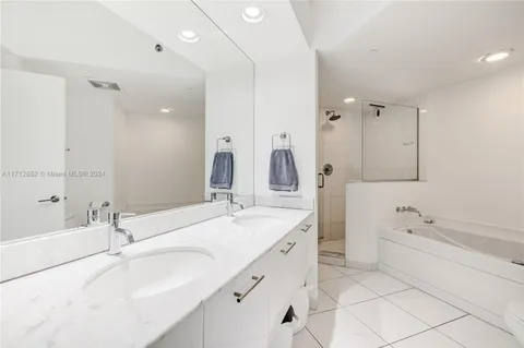 a bathroom with a sink double vanity granite tub shower and a mirror
