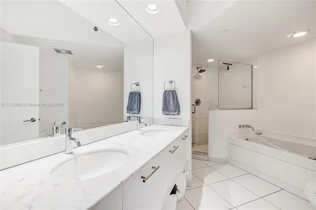 a bathroom with a sink double vanity granite tub shower and a mirror