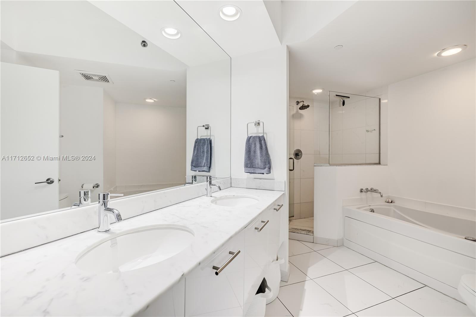 55 Southeast 6th Street, Unit 3407 Miami, FL 33131 - Photo 13 of 33 a bathroom with a sink double vanity granite tub shower and a mirror