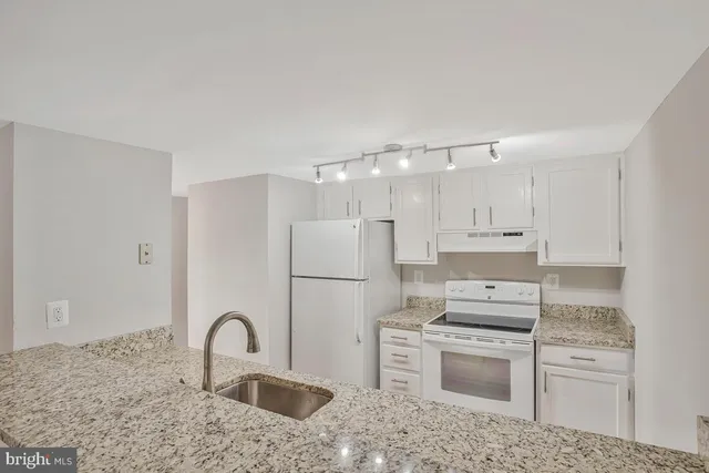 a kitchen with kitchen island a refrigerator stove and sink