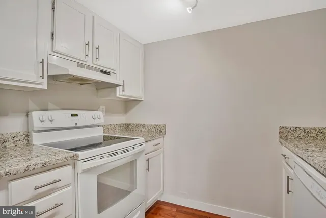 a kitchen with granite countertop white cabinets and white appliances