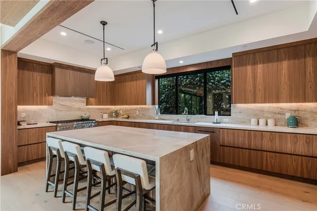 a kitchen with stainless steel appliances a table chairs sink and wooden floor
