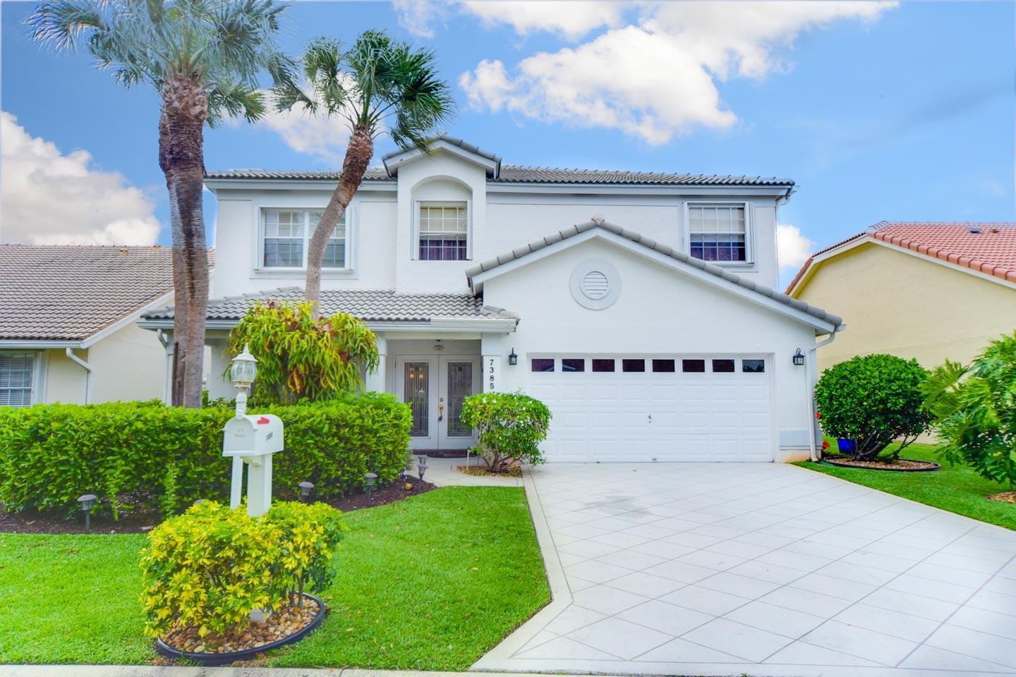 7385 Shell Ridge Terrace Lake Worth, FL 33467 - Photo 1 of 1 a view of a white house with a big yard and potted plants