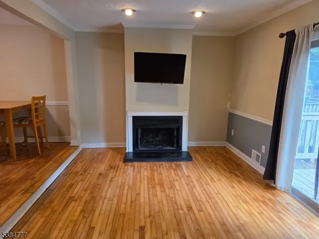 a view of a livingroom with wooden floor and a fireplace