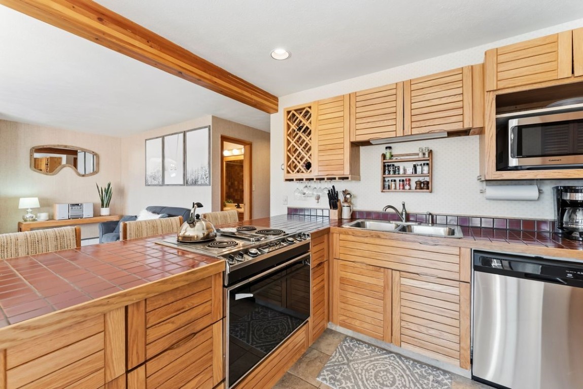 91300 Ryan Gulch Road, Unit 91311 Silverthorne, CO 80498 - Photo 11 of 28 a kitchen with stainless steel appliances granite countertop a stove a sink and a microwave