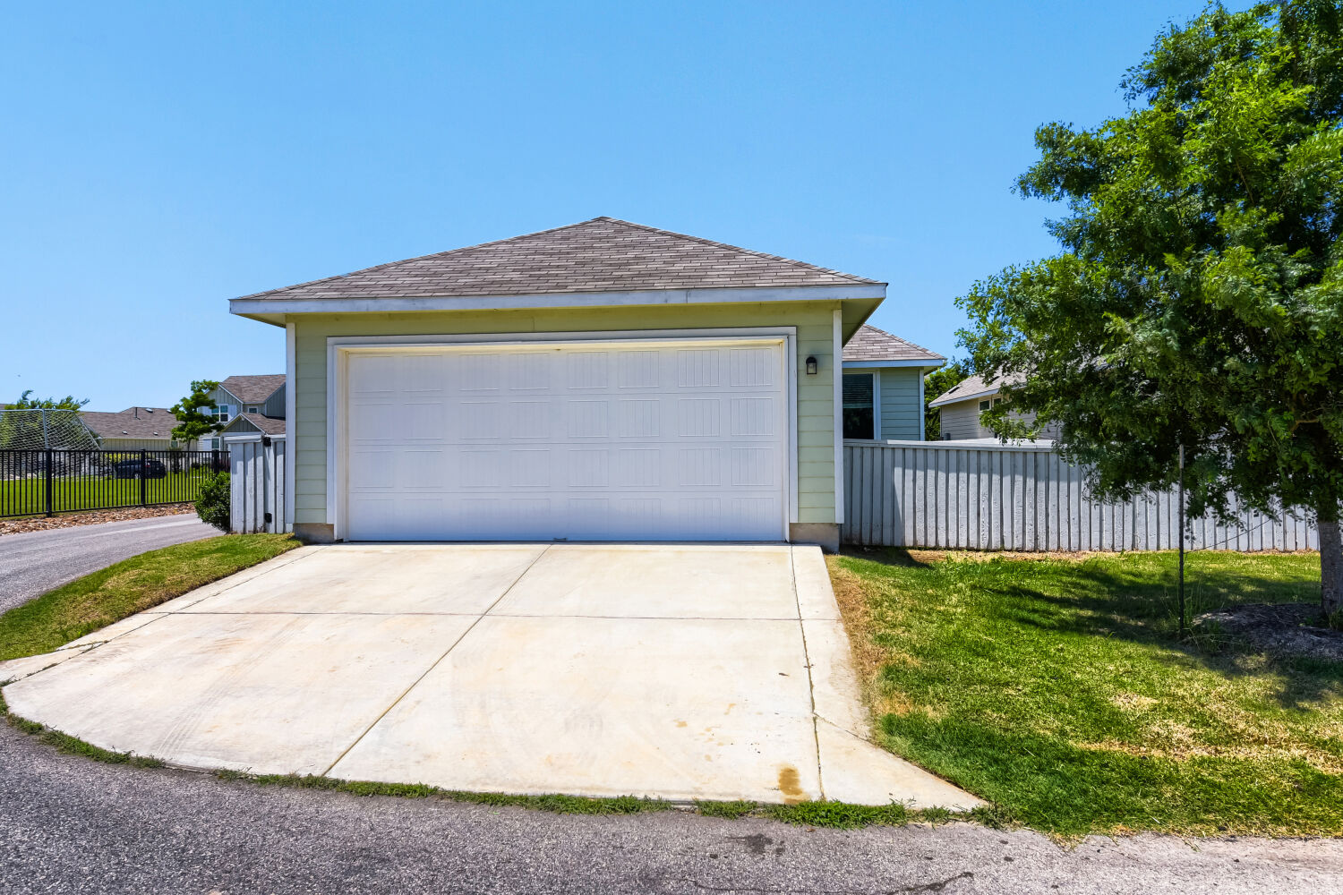 1310 Goforth Road Kyle, TX 78640 - Photo 23 of 24 Attached two-car garage with a concrete driveway and light green siding