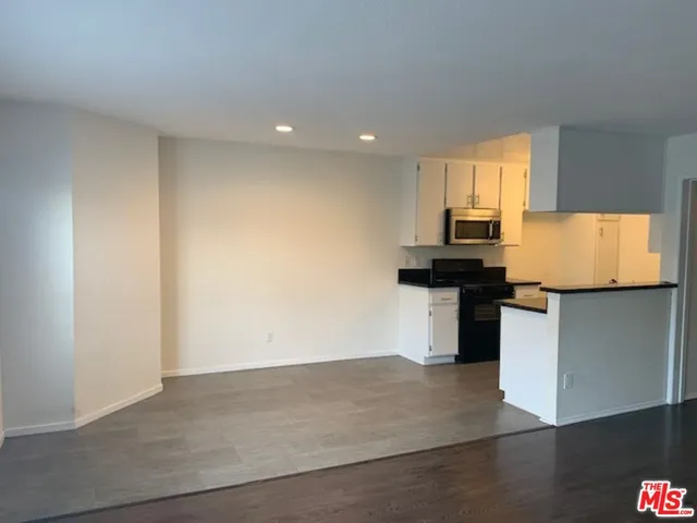 an empty room with wooden floor mirror and windows