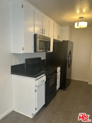 a view of an empty room with wooden floor and closet