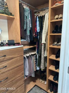 a view of walk in closet with clothes and shoes