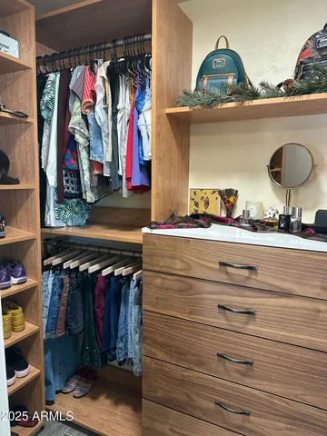a view of walk in closet with clothes and shoes
