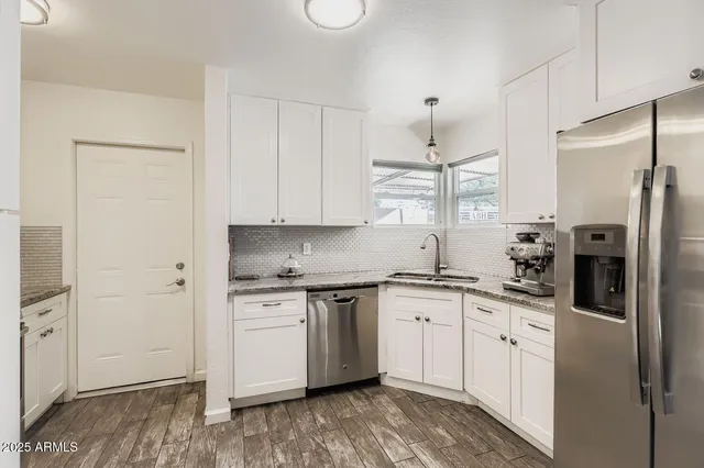a kitchen with stainless steel appliances granite countertop a refrigerator sink and white cabinets