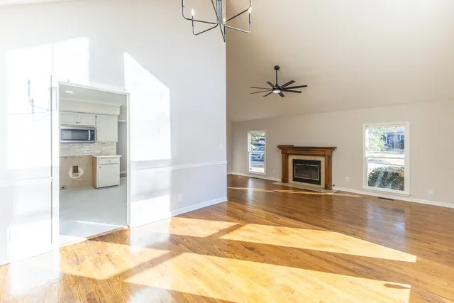 a view of a livingroom with a fireplace a ceiling fan and windows