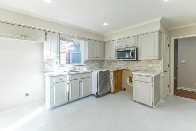 a kitchen with white cabinets sink and stainless steel appliances