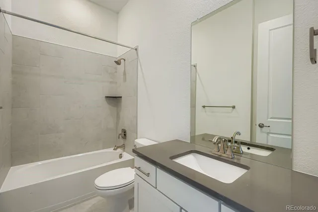 a bathroom with a granite countertop sink toilet and shower