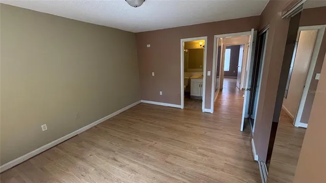 a view of an empty room with wooden floor and a mirror