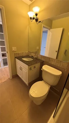 a bathroom with a granite countertop toilet sink and mirror
