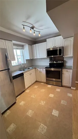 a large white kitchen with a stove top oven a sink and dishwasher
