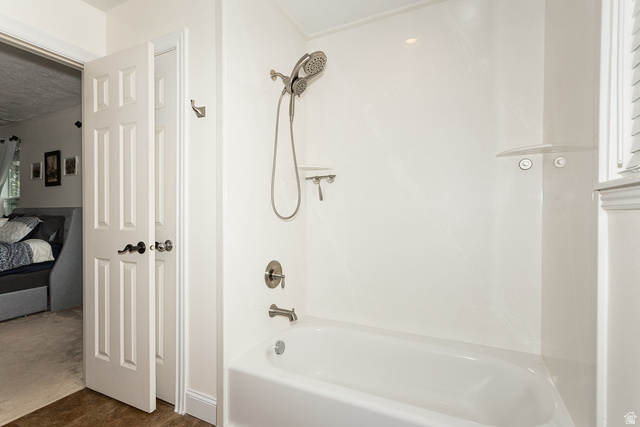 7797 North Windhover Road Eagle Mountain, UT 84005 - Photo 19 of 33 White bathtub and shower combination featuring brushed nickel fixtures, a multi-setting showerhead, and integrated shelving