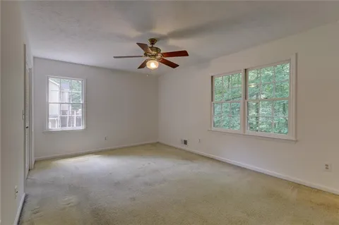 an empty room with windows and fan