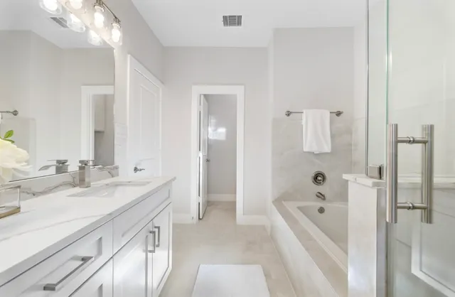 a spacious bathroom with a tub sink and mirror