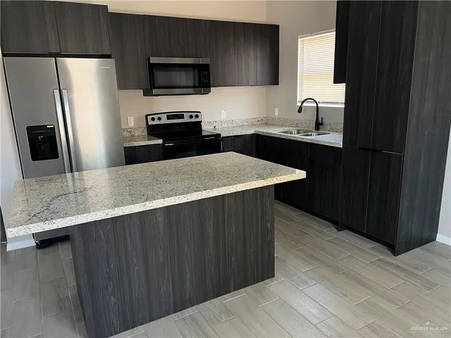 a kitchen with stainless steel appliances a sink dishwasher a refrigerator microwave and stove with wooden floor