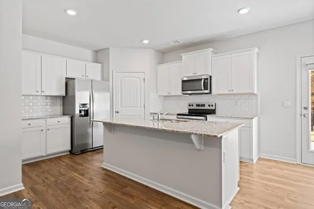 a kitchen with granite countertop a refrigerator stove top oven and sink