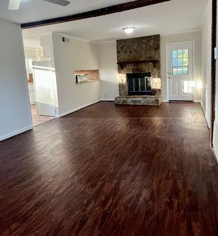 an empty room with wooden floor a fireplace and windows