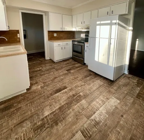 a kitchen with granite countertop a refrigerator sink and white cabinets